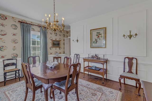 dining area with hardwood / wood-style floors, ornamental molding, and an inviting chandelier