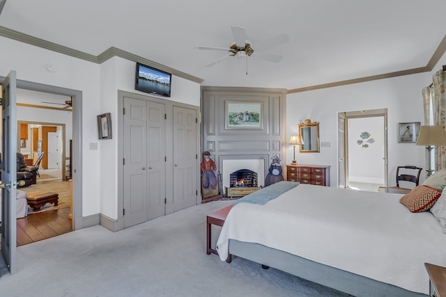 bedroom featuring light carpet, a large fireplace, ceiling fan, and crown molding