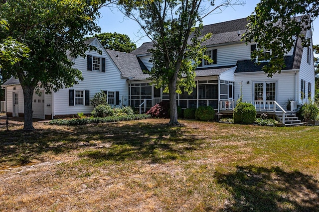 rear view of house featuring a deck, a lawn, and a sunroom