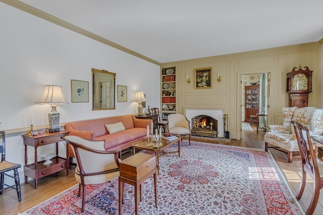 living room with built in shelves, light hardwood / wood-style flooring, and crown molding