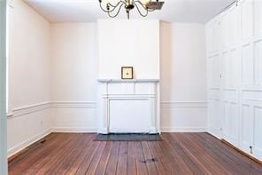 525 Main St, Mathews, VA 23109 - unfurnished living room with an inviting chandelier, baseboards, and dark wood-style floors