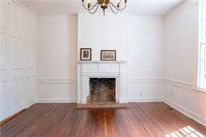 525 Main St, Mathews, VA 23109 - unfurnished living room with baseboards, a fireplace with flush hearth, wood finished floors, and a notable chandelier