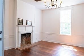 525 Main St, Mathews, VA 23109 - unfurnished living room featuring an inviting chandelier, baseboards, a fireplace, and wood finished floors