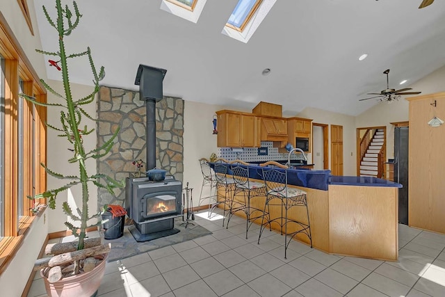10114 New Hope Ct, Gloucester, VA 23061 - kitchen with a wood stove, vaulted ceiling, light tile patterned floors, black appliances, and a peninsula