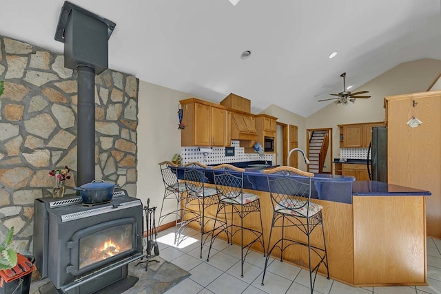 10114 New Hope Ct, Gloucester, VA 23061 - kitchen featuring a wood stove, black appliances, backsplash, a ceiling fan, and light tile patterned floors