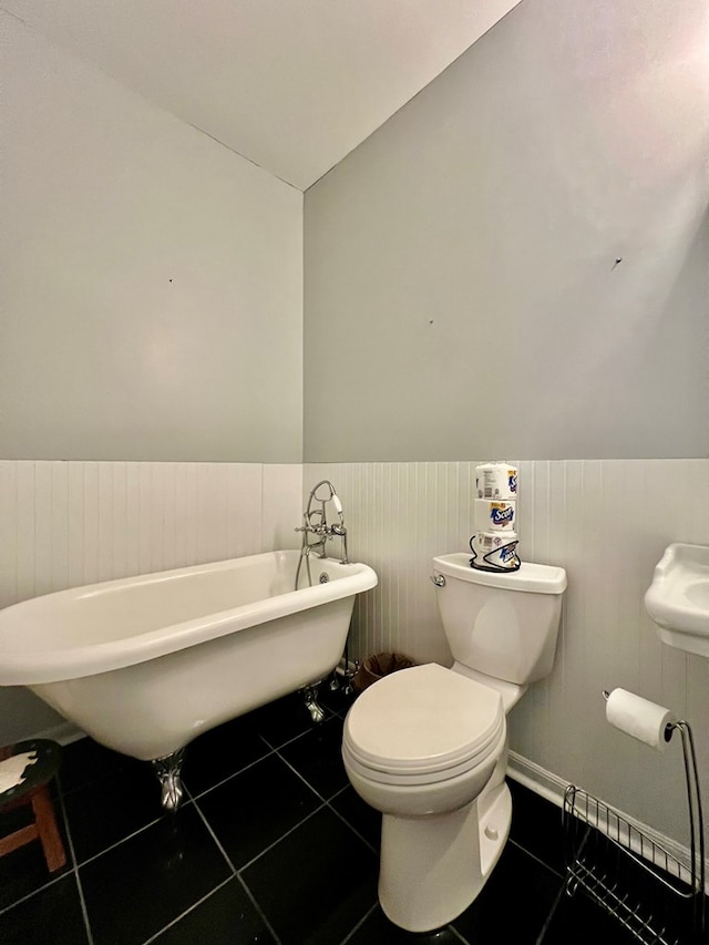 bathroom featuring a washtub, tile patterned flooring, and toilet