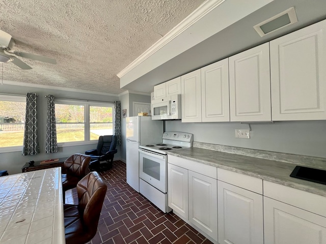 kitchen with a textured ceiling, crown molding, white cabinets, and white appliances