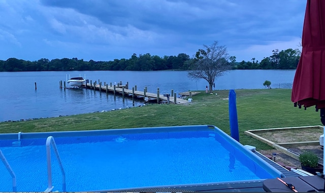 view of swimming pool featuring a water view, a dock, and a lawn