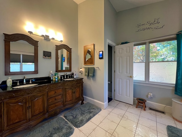 bathroom with tile patterned flooring, vanity, and a healthy amount of sunlight