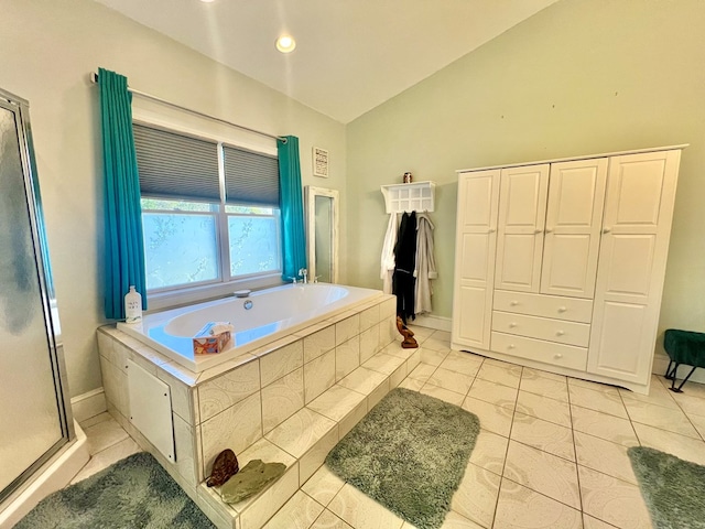 bathroom with tile patterned flooring, a relaxing tiled tub, and lofted ceiling