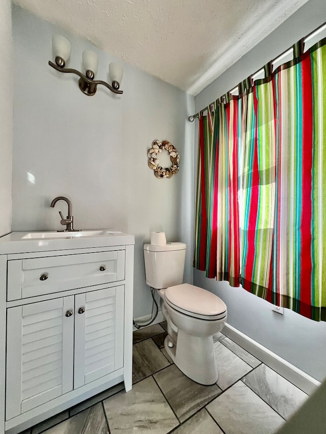 bathroom featuring vanity, a textured ceiling, and toilet