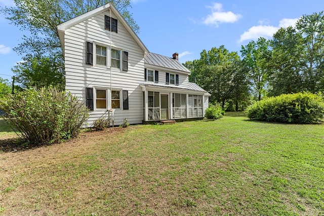 1838 Muddy Gut Rd, Dunnsville, VA 22454 - rear view of house with a chimney, a sunroom, a lawn, a metal roof, and a standing seam roof