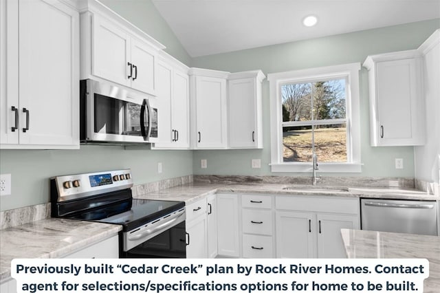 kitchen with lofted ceiling, sink, white cabinets, stainless steel appliances, and light stone countertops