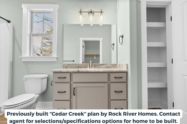 bathroom featuring built in shelves, vanity, and toilet