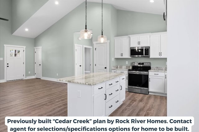 kitchen featuring stainless steel appliances, white cabinetry, light stone countertops, and a center island