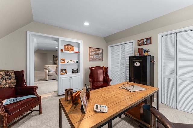 office area featuring built in shelves, light colored carpet, and vaulted ceiling