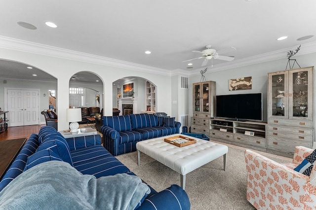 living room featuring a fireplace, hardwood / wood-style floors, ceiling fan, and crown molding