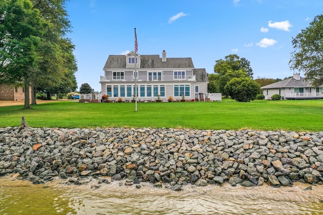 back of house with a water view and a lawn