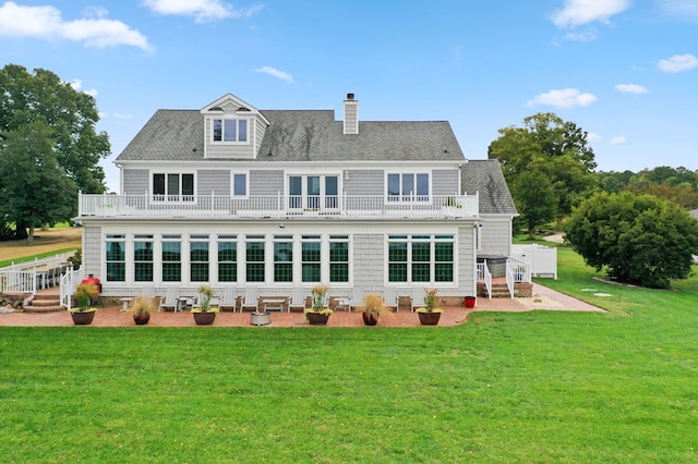 rear view of property featuring a yard, a balcony, and a patio