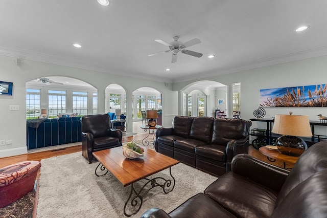 living room featuring ceiling fan, light hardwood / wood-style floors, ornate columns, and crown molding