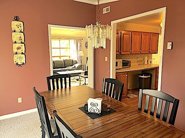 dining area with crown molding and a chandelier