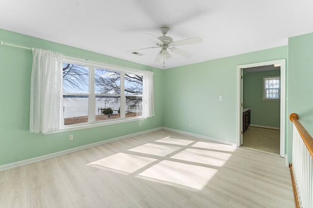 spare room with visible vents, baseboards, wood finished floors, and a ceiling fan