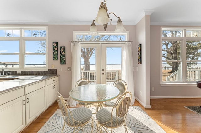 dining room with light wood-style flooring, french doors, baseboards, and ornamental molding