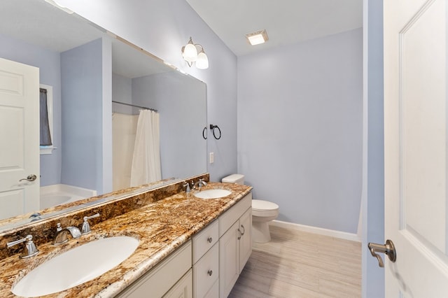 full bath featuring double vanity, toilet, baseboards, and a sink