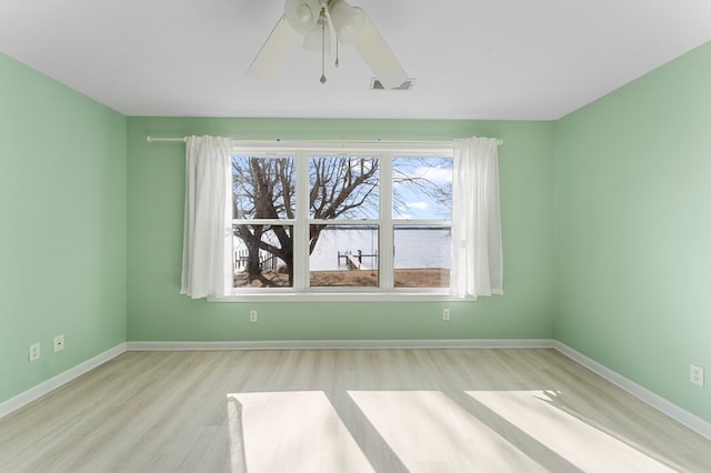 spare room featuring ceiling fan, visible vents, baseboards, and wood finished floors