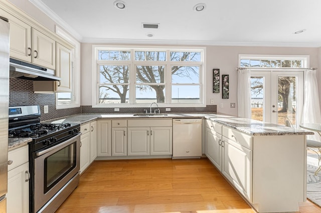 kitchen with visible vents, crown molding, under cabinet range hood, white dishwasher, and stainless steel gas range