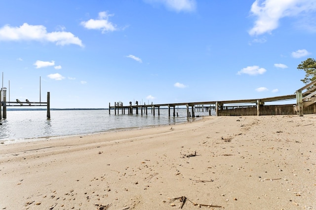 view of dock featuring a beach view and a water view