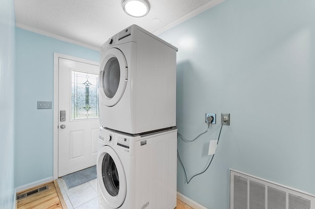 844 Monarch Shores Rd, Kilmarnock, VA 22482 - laundry area featuring stacked washer and clothes dryer, crown molding, baseboards, light wood-style flooring, and a textured ceiling