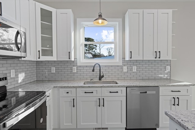 kitchen featuring backsplash, pendant lighting, sink, white cabinetry, and appliances with stainless steel finishes