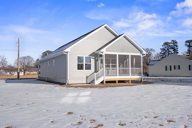 snow covered house featuring a sunroom