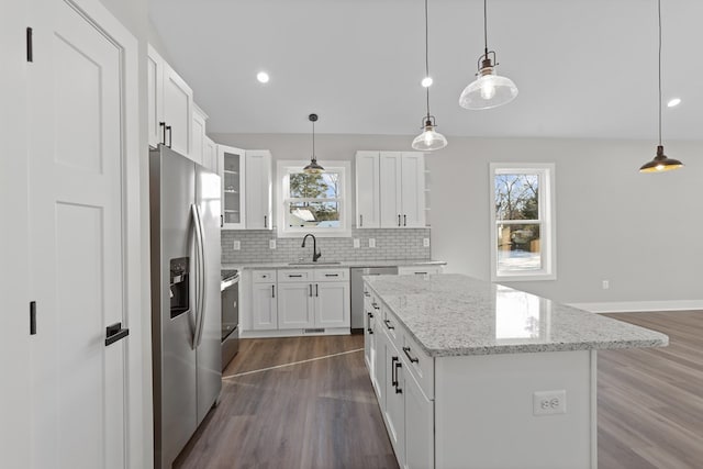 kitchen featuring appliances with stainless steel finishes, pendant lighting, white cabinetry, and a center island