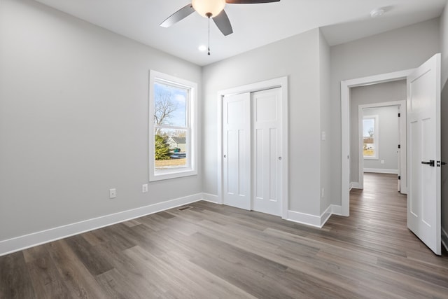 unfurnished bedroom with ceiling fan, a closet, and hardwood / wood-style flooring