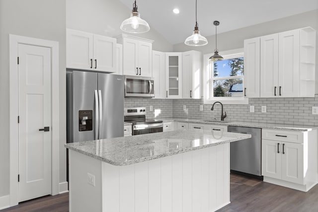 kitchen featuring appliances with stainless steel finishes, a center island, white cabinetry, sink, and vaulted ceiling