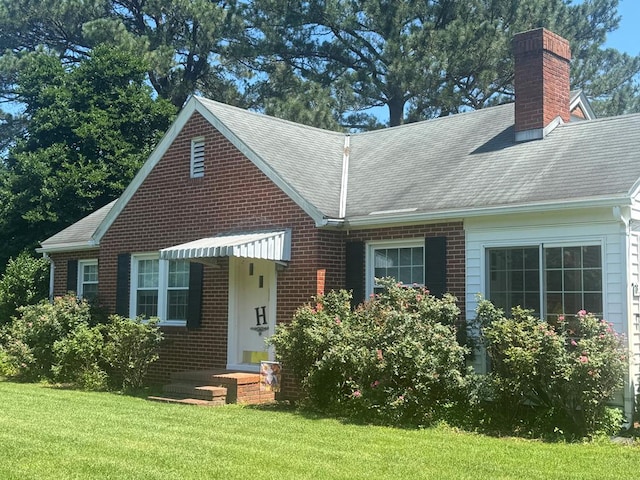 4503 Buckley Hall Rd, Cobbs Creek, VA 23035 - view of front of home with a chimney, brick siding, a front yard, and a shingled roof