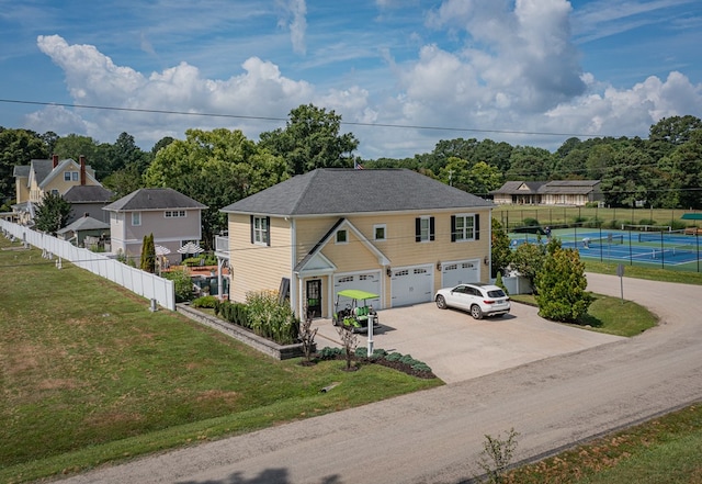 view of front of house featuring tennis court, a garage, and a front yard