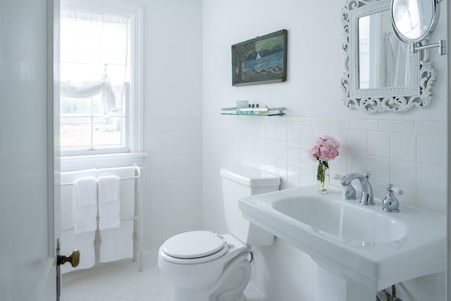 bathroom featuring toilet, plenty of natural light, tile walls, and sink