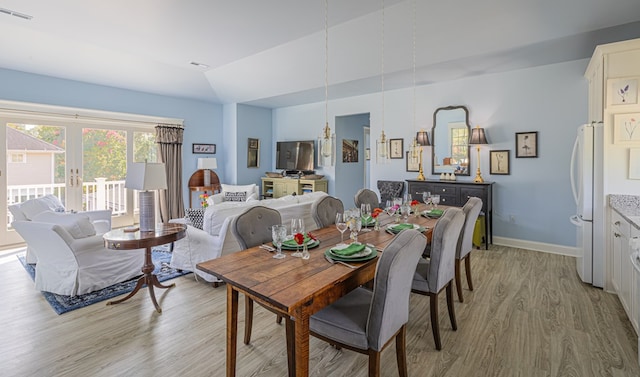 dining space with french doors, light hardwood / wood-style floors, and lofted ceiling