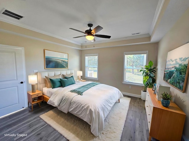 bedroom with a raised ceiling, crown molding, dark hardwood / wood-style floors, and ceiling fan