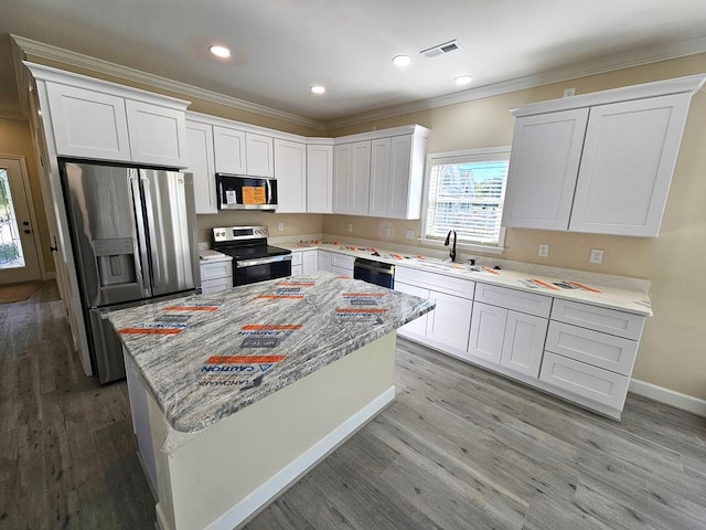 kitchen featuring light hardwood / wood-style flooring, appliances with stainless steel finishes, light stone counters, white cabinets, and a kitchen island