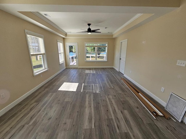 unfurnished living room featuring dark hardwood / wood-style flooring, a tray ceiling, crown molding, and ceiling fan