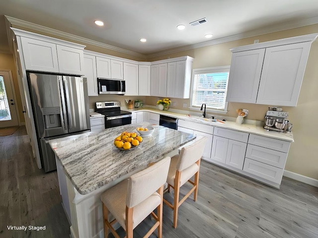 kitchen with sink, a center island, white cabinets, and appliances with stainless steel finishes