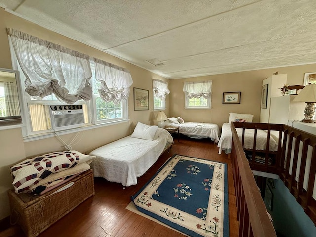 bedroom featuring multiple windows, a textured ceiling, and hardwood / wood-style flooring