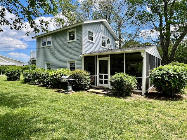rear view of house featuring a sunroom and a lawn
