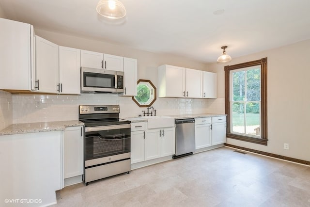 kitchen featuring decorative backsplash, stainless steel appliances, sink, pendant lighting, and white cabinetry