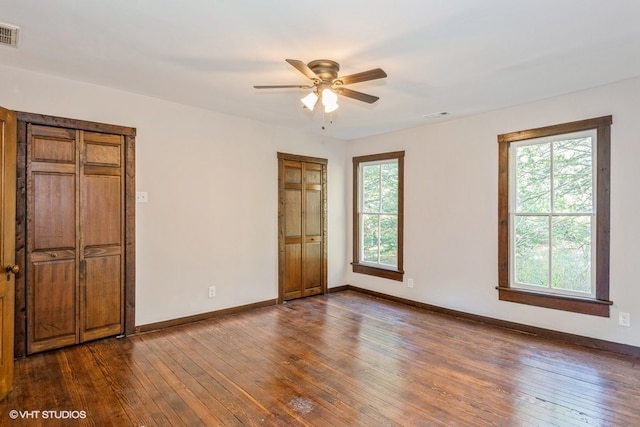 unfurnished bedroom with multiple windows, ceiling fan, and dark hardwood / wood-style flooring