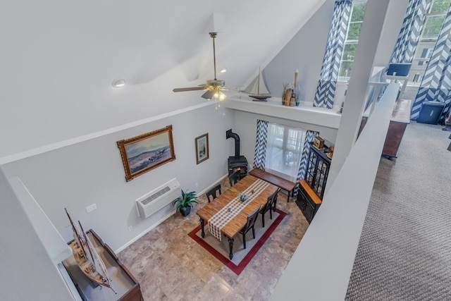 living room with a wall unit AC, a wood stove, and ceiling fan